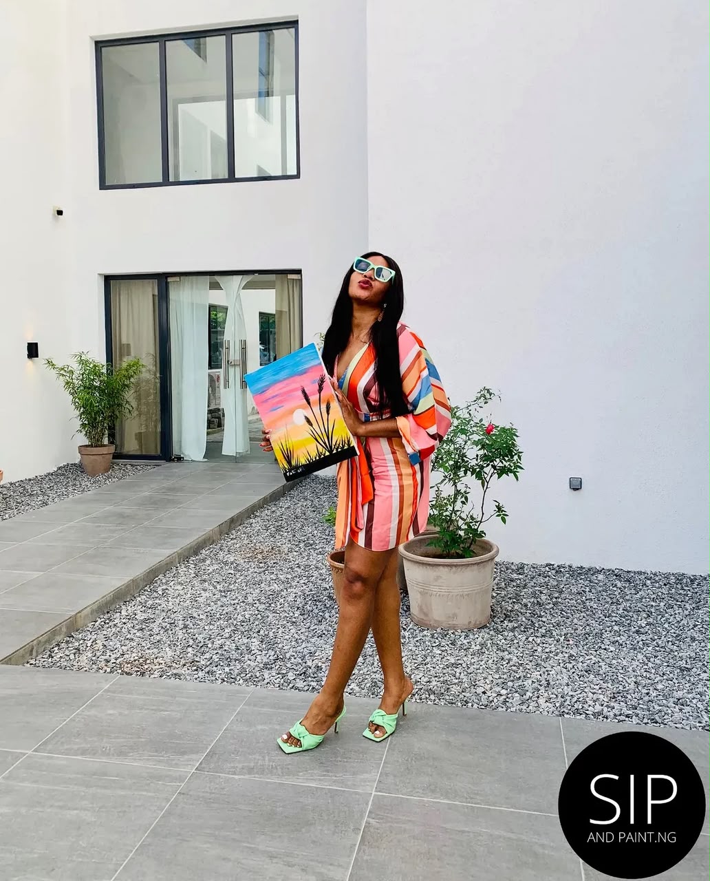 A guest posing outdoors in Abuja with her finished sunset canvas painting
