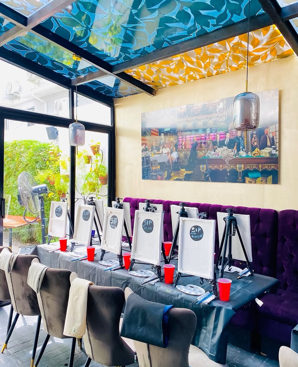 A row of blank canvases on easels set up along a purple velvet booth for a Sip and Paint Abuja session